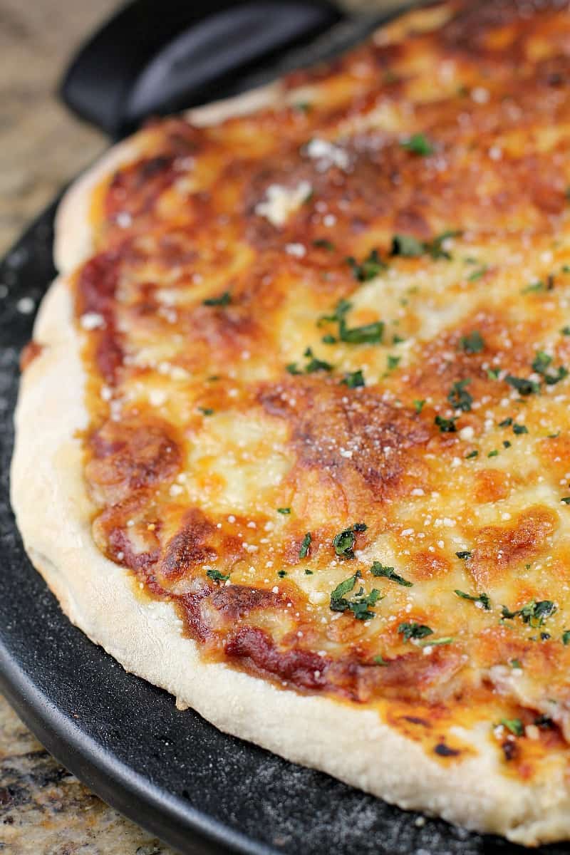 cooked cheese pizza on black pizza stone