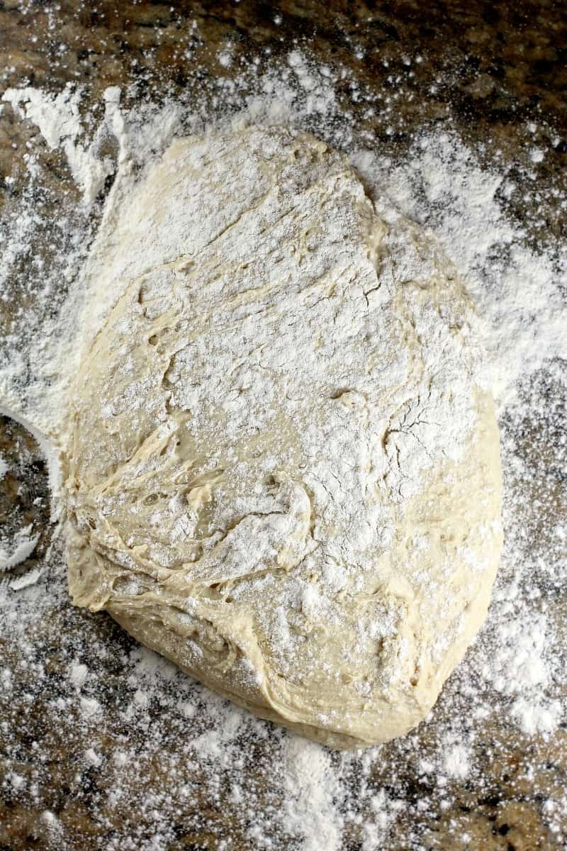 risen dough on marble surface with flour sprinkled over top