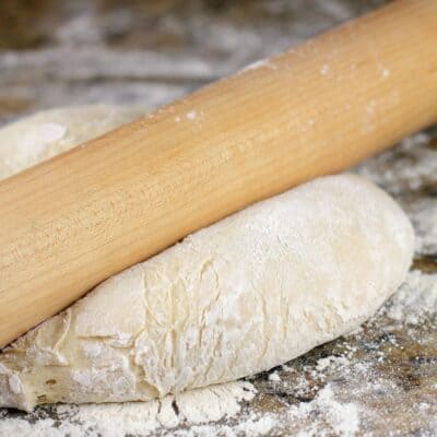 rolling pin pressing on pizza dough