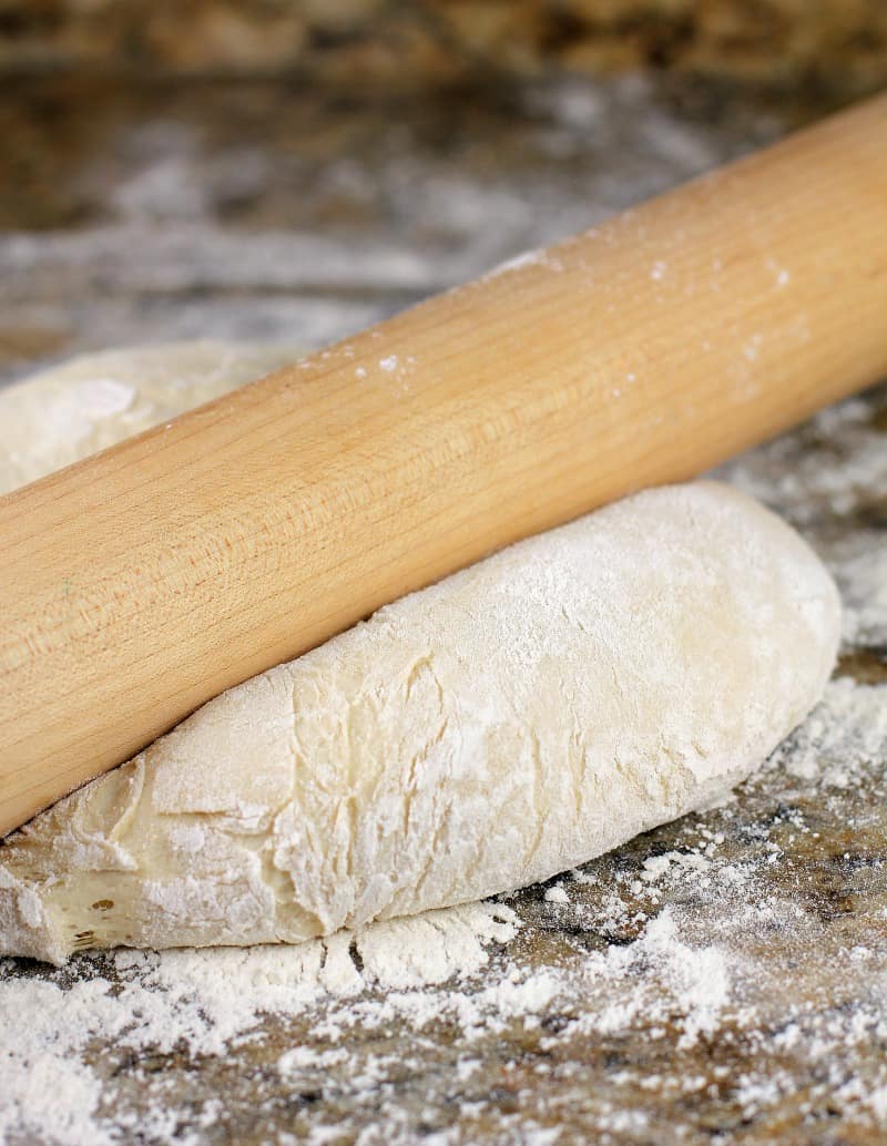 rolling pin pressing on pizza dough