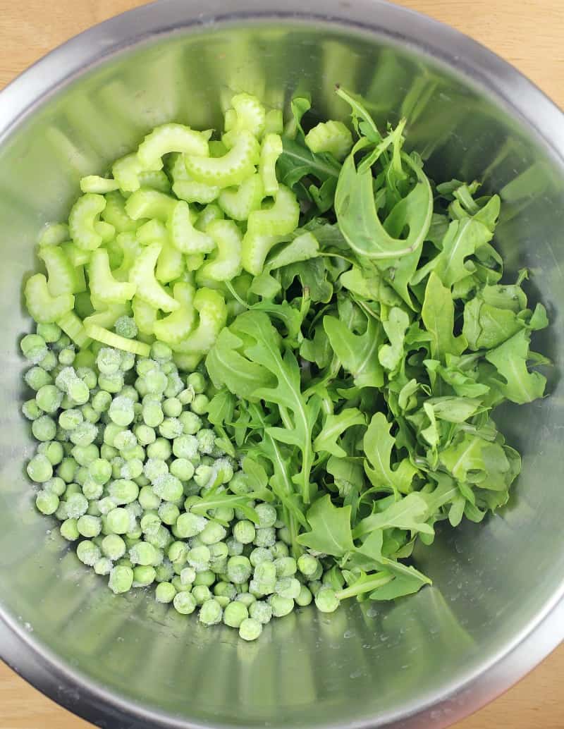 celery, peas, and arugula in a metal bowl
