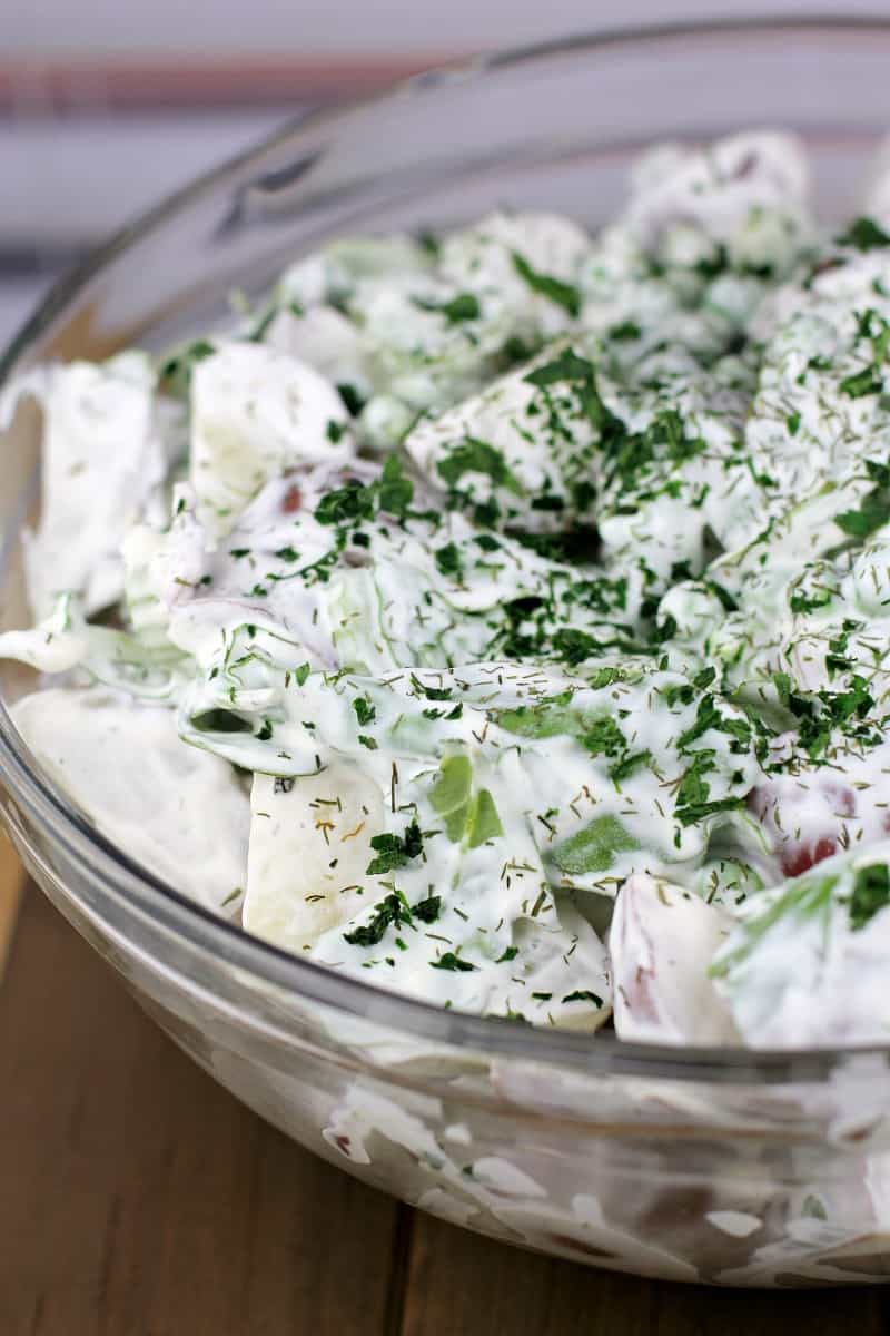 potato salad with dill in a bowl on a wood surface