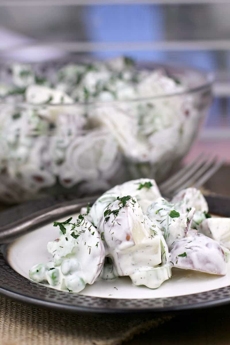 plated potato salad with sour cream, large bowl in the background