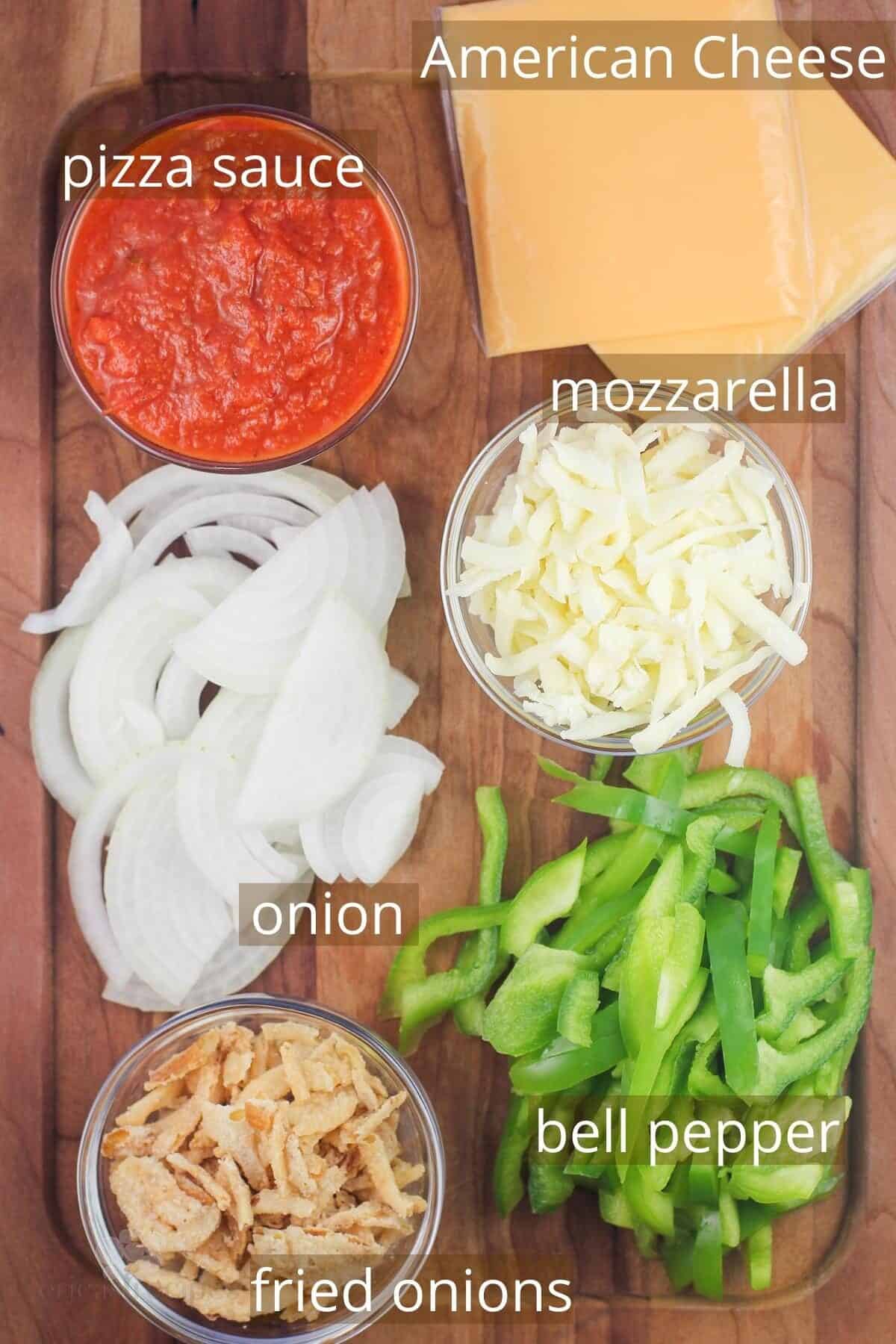recipe ingredients on board and labeled: pizza sauce, american cheese, mozzarella, onion, bell pepper, and fried onions