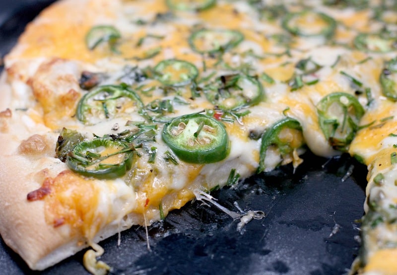 side view of the finished jalapeno pizza, sliced to show the cooked toppings and melty cheese