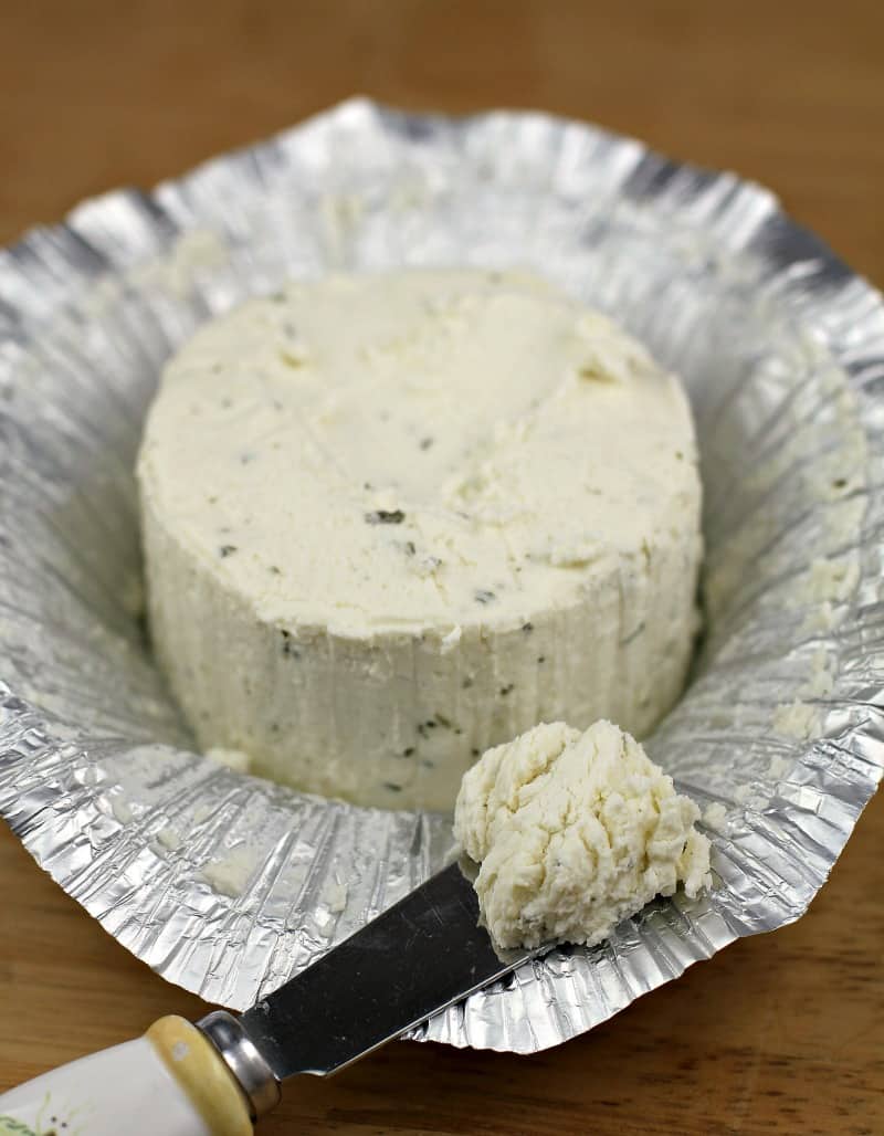 boursin cheese sitting on open foil with a butter knife