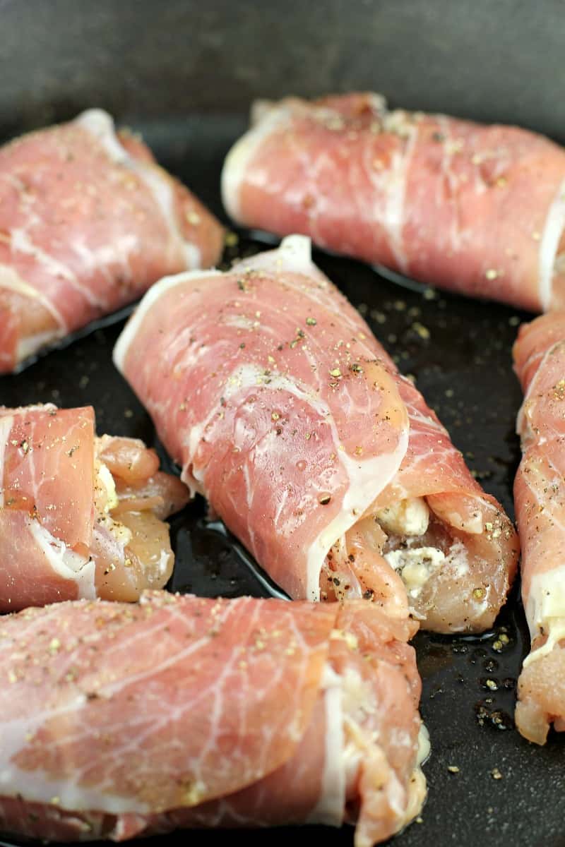 assembled boursin-stuffed chicken, wrapped with prosciutto, in a cook pan