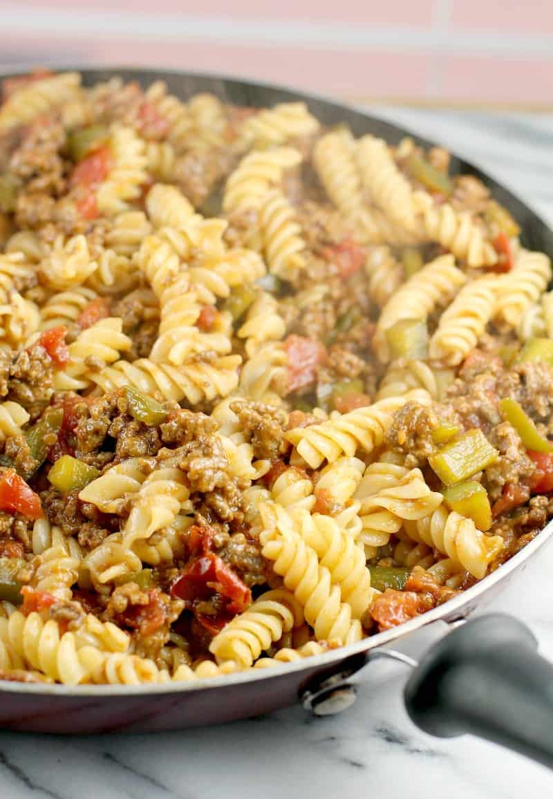 side view of the fully assembled sloppy joe dinner in a skillet placed on white marble