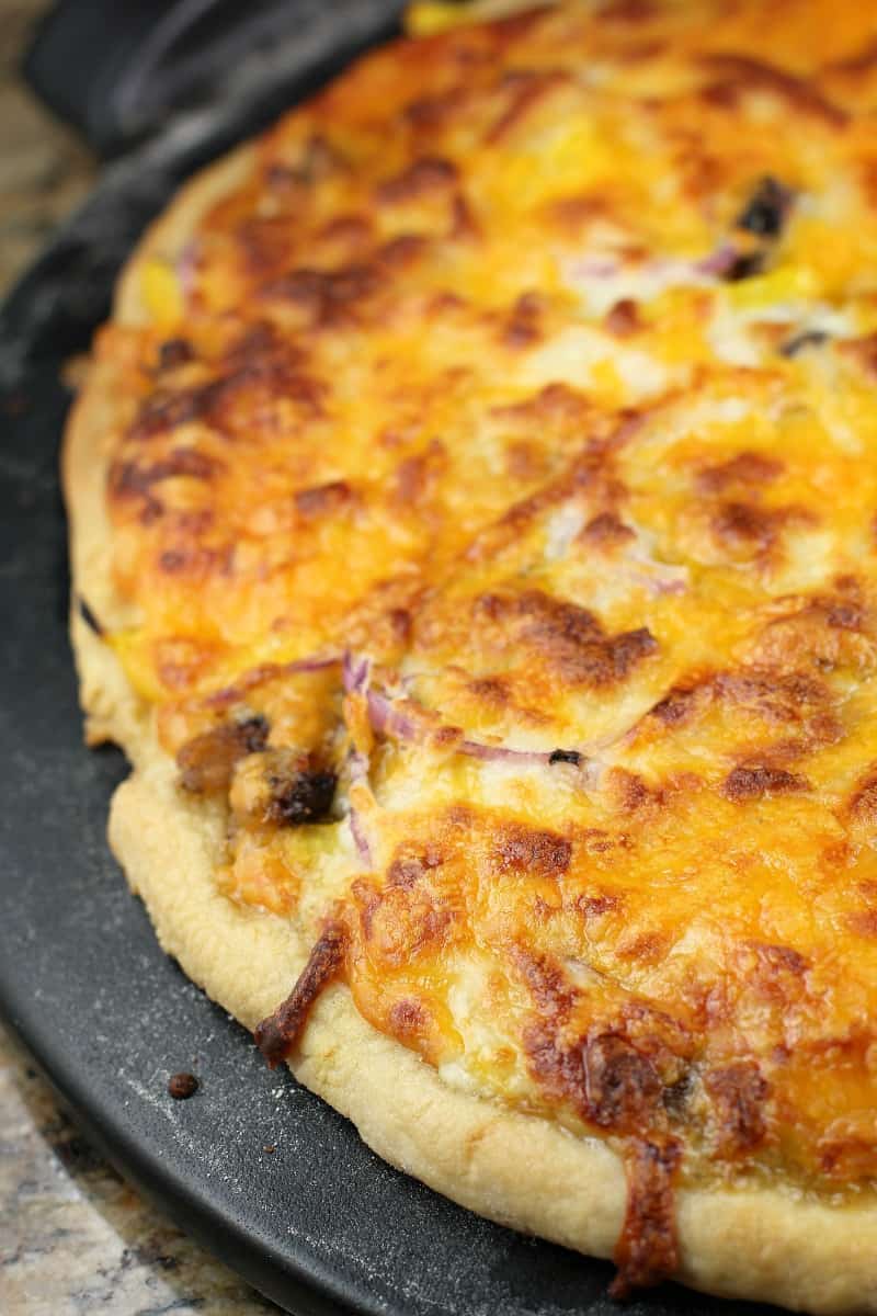 cooked bbq pizza on a black pizza stone