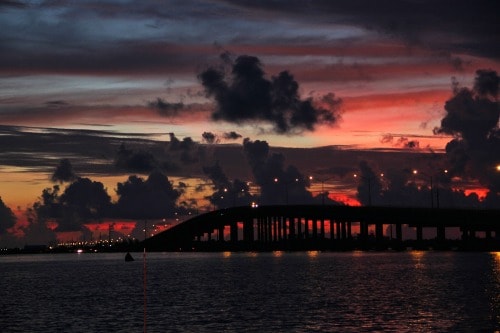 view of a bridge at sunrise over the intercoastal waterway. still dark out with a red sky on the horizon