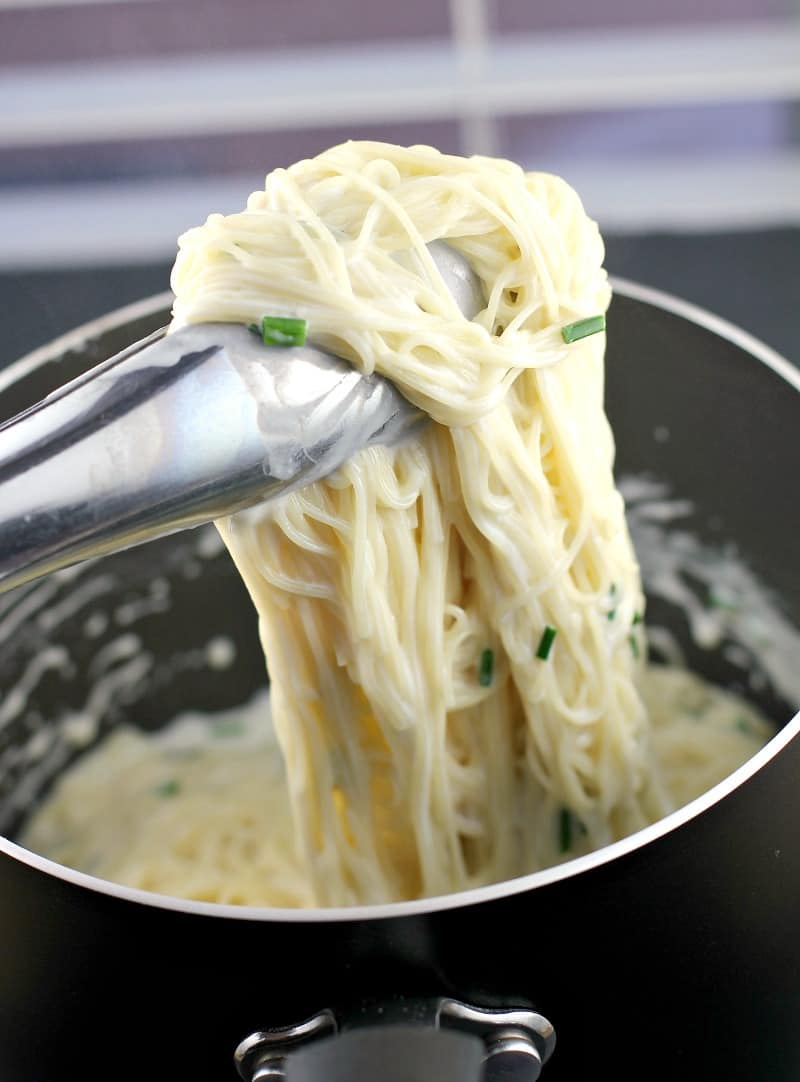 thongs lifting up sour cream pasta from place saucepan