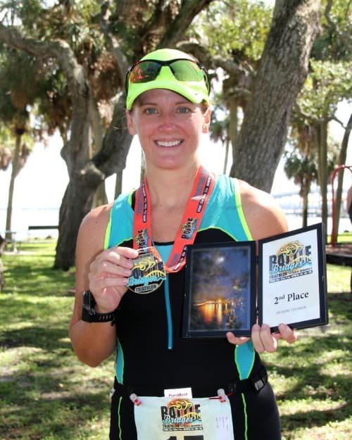 picture of the author after a triathlon holding a medal and award