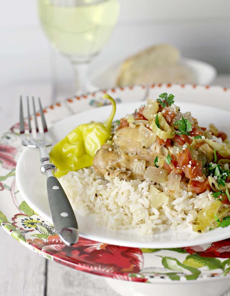 side view showing cooked Italian pulled chicken served over rice. Bread and lass of white wine are in the background.