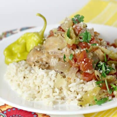 side view showing cooked Italian pulled chicken slow cooker served over rice on a white dish on top of a a yellow napkin.