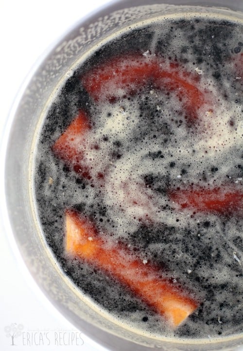 top down view of the polska kielbasa simmering in beer in a pot; white background