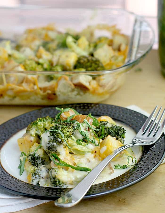 broccoli cheese casserole on a rimmed dish with fork, casserole dish in the background