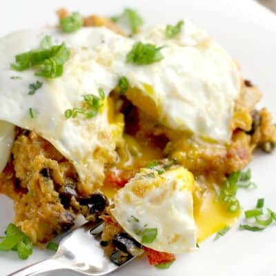 fork holding a bite sized amount of casserole topped with egg