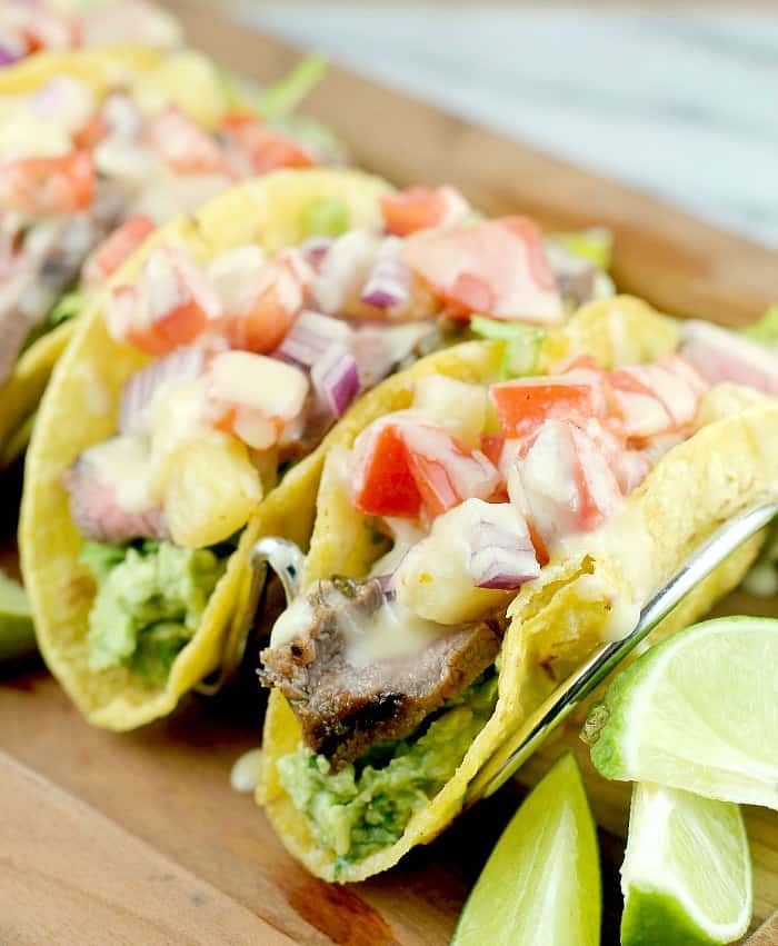 three finished tacos in a rack on a wood serving plate