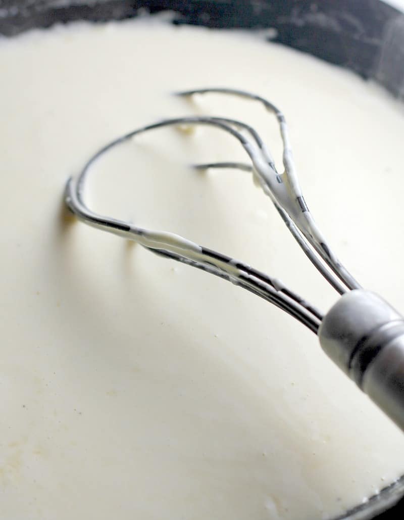 a whisk stirring cream sauce