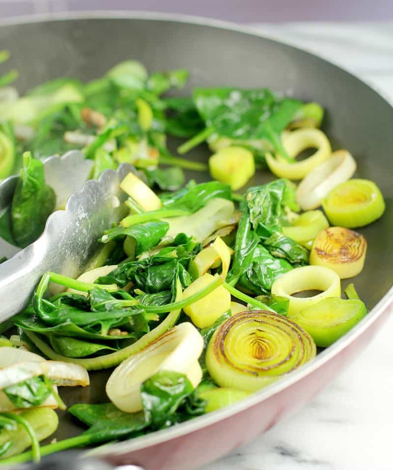 spinach and leeks cooking in a skillet