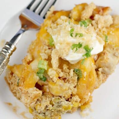 Top down view of finished casserole plated on a white plate, topped with sour cream and pork rind crumbs