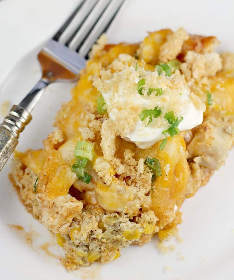 Top down view of finished casserole plated on a white plate, topped with sour cream and pork rind crumbs