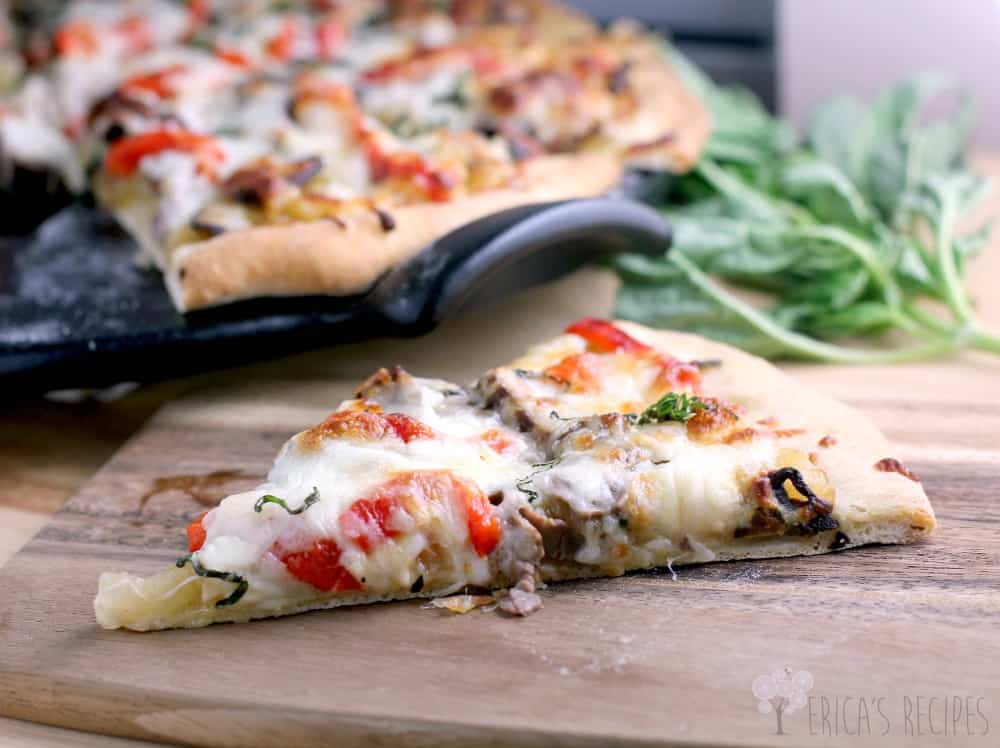 angled side view of a slice of French Onion Pizza on a cutting board