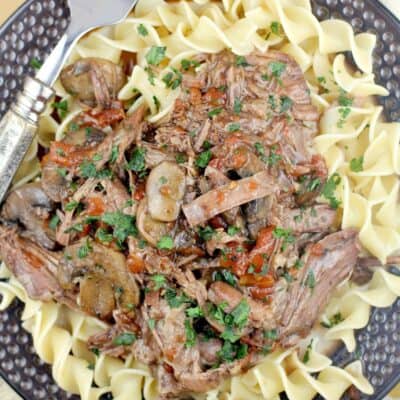 top down view of the cajun instant pot pot roast on a brown plate over noodles