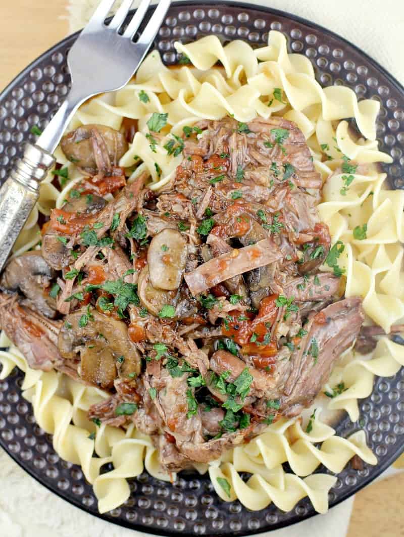 top down view of the cajun instant pot pot roast on a brown plate over noodles