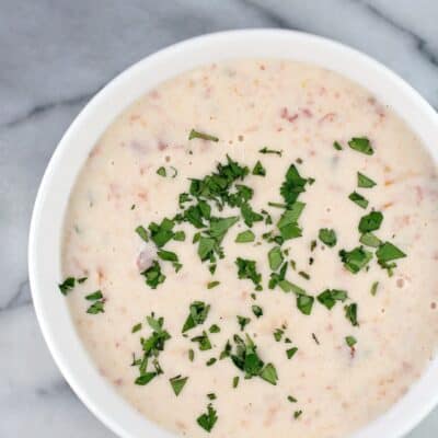 top down view of a bowl full of white queso dip, cilantro scatter on top, bowl is on a marble surface