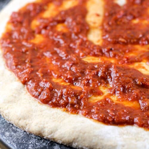 homemade pizza sauce on uncooked pizza dough