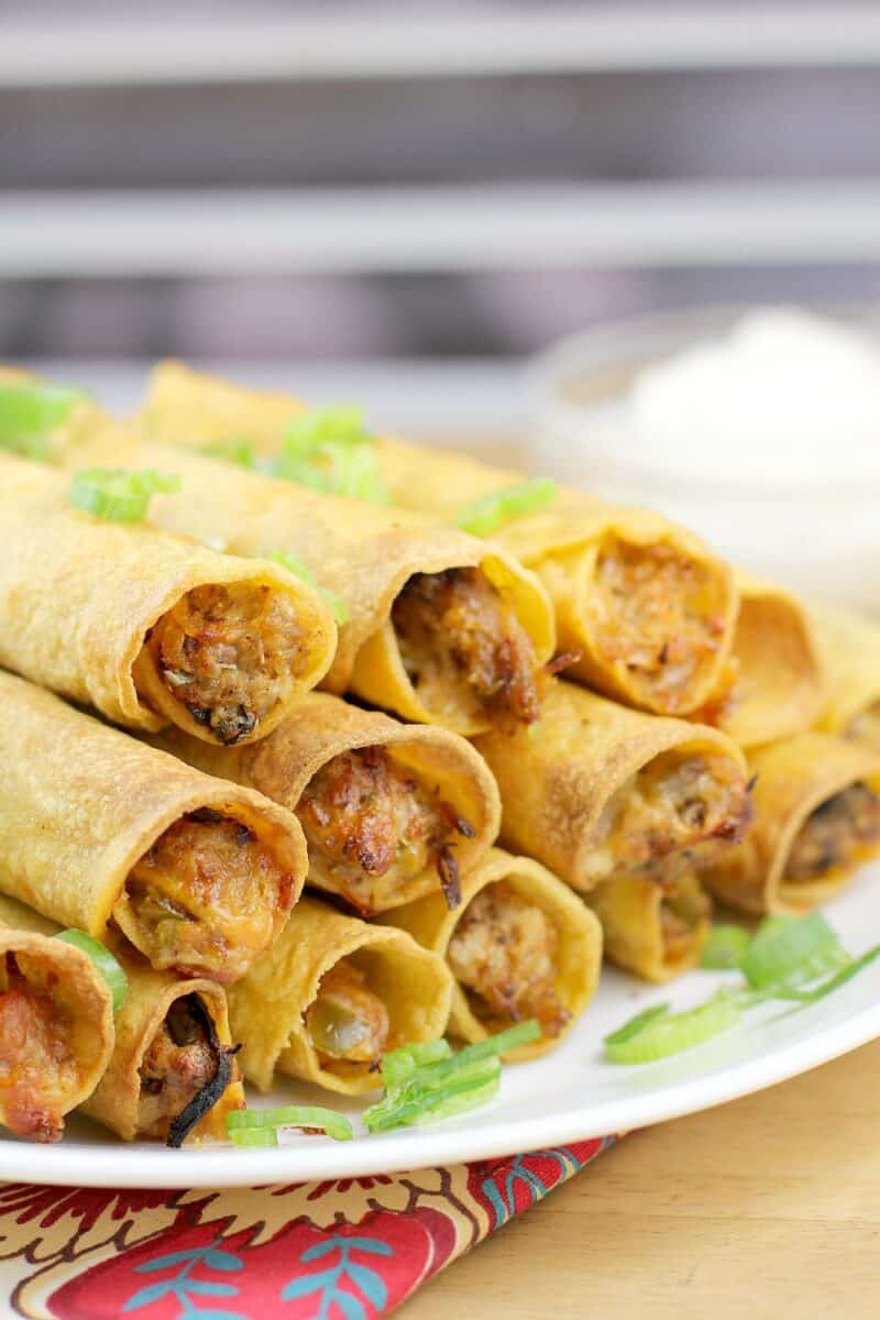 side view of taquitos on a white dish