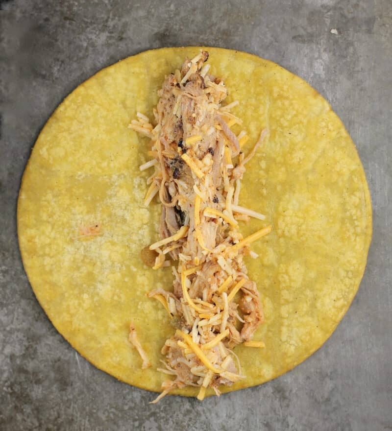 pulled pork filling down the center of a corn tortilla