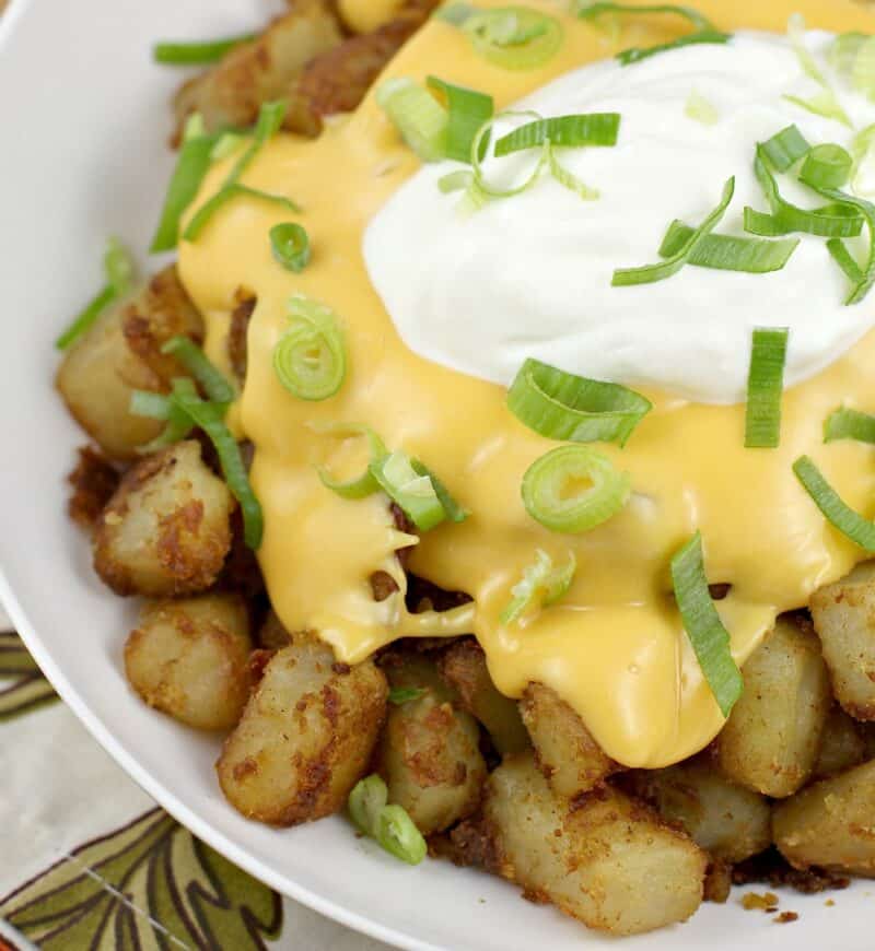potatoes topped with cheese and sour cream in a white bowl