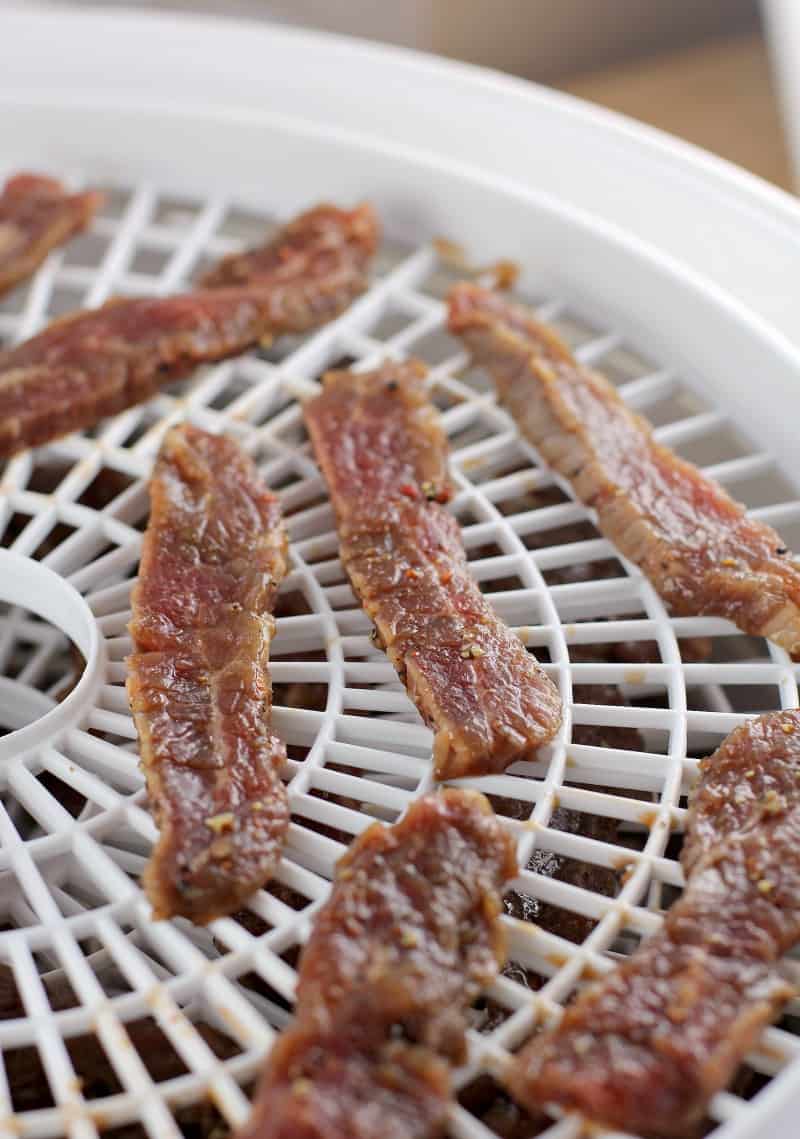 beer bbq jerky strips on white dehydrator rack