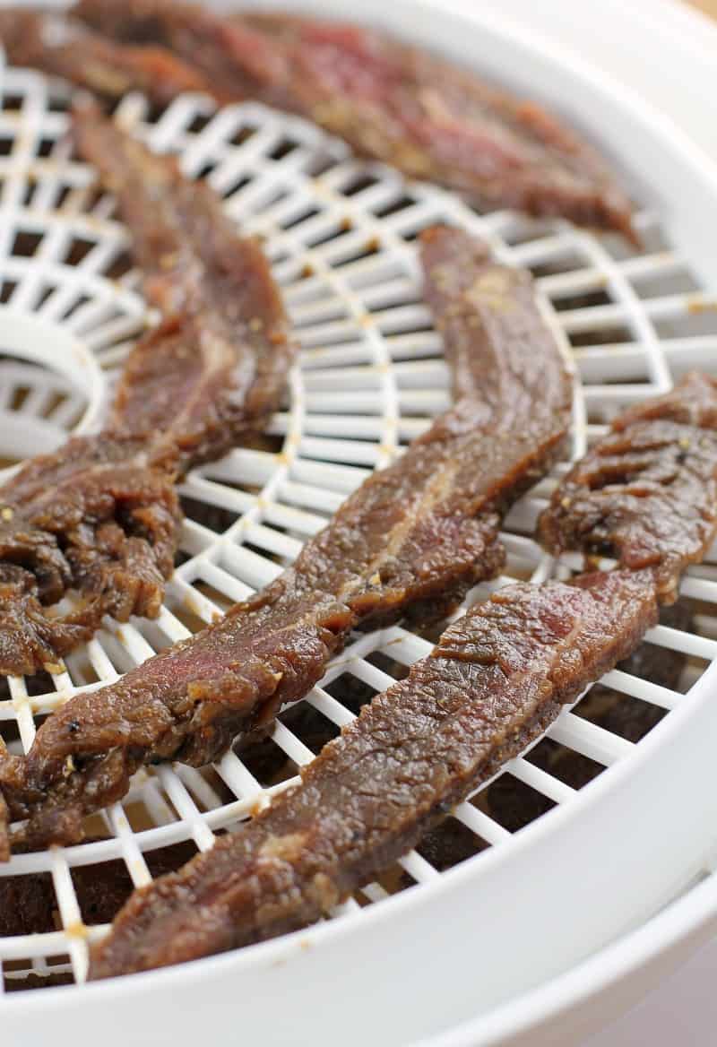 teriyaki jerky strips on white dehydrator rack