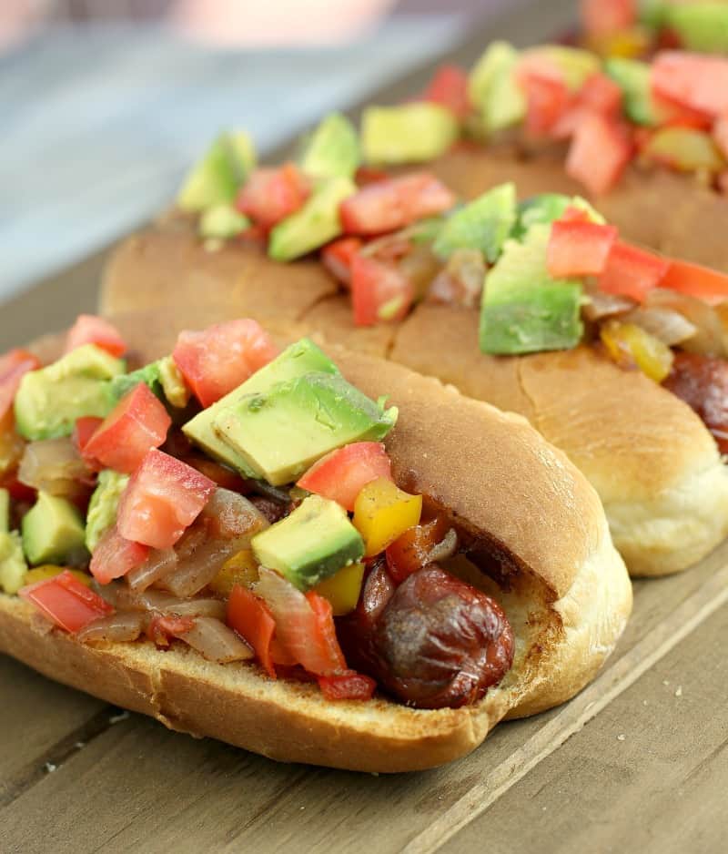 row of hot dogs with toppings on a wood board
