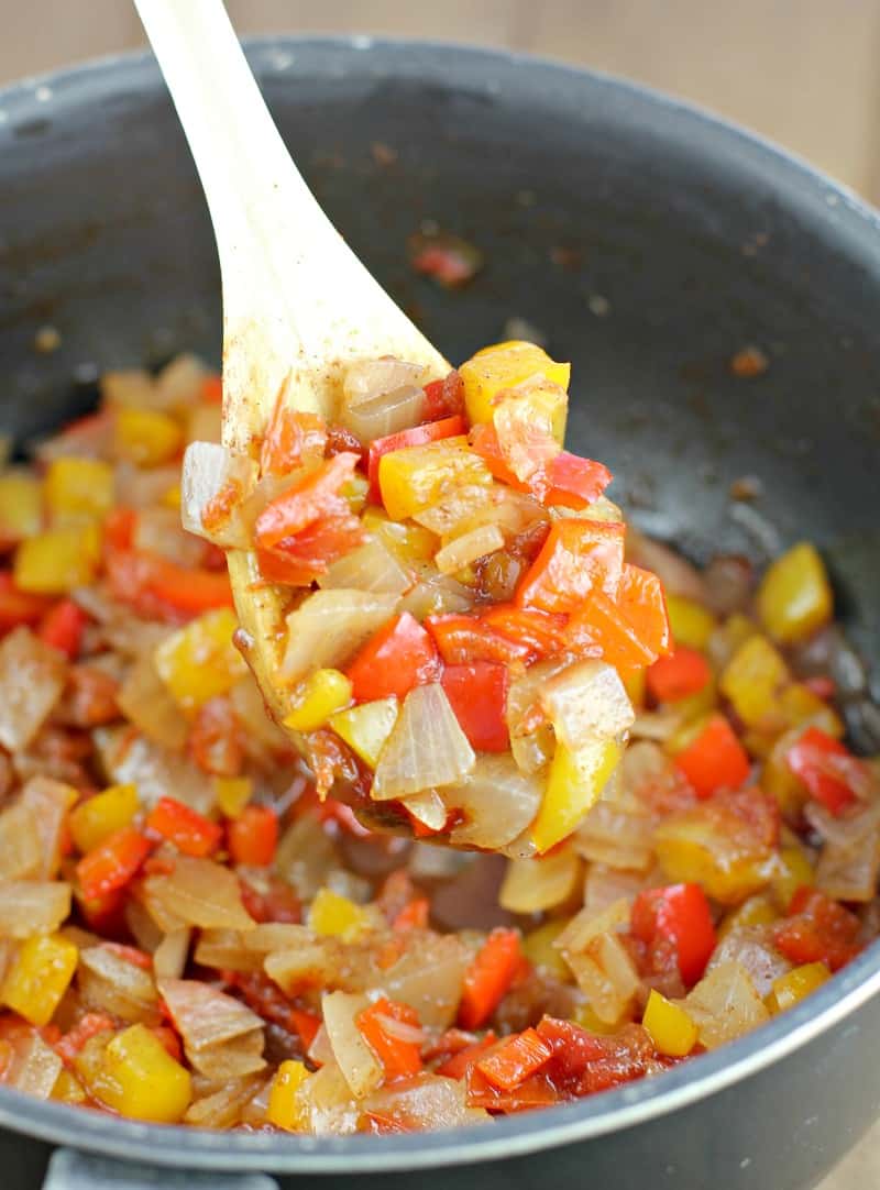 spoon scooping sweet pepper relish in a black saucepan