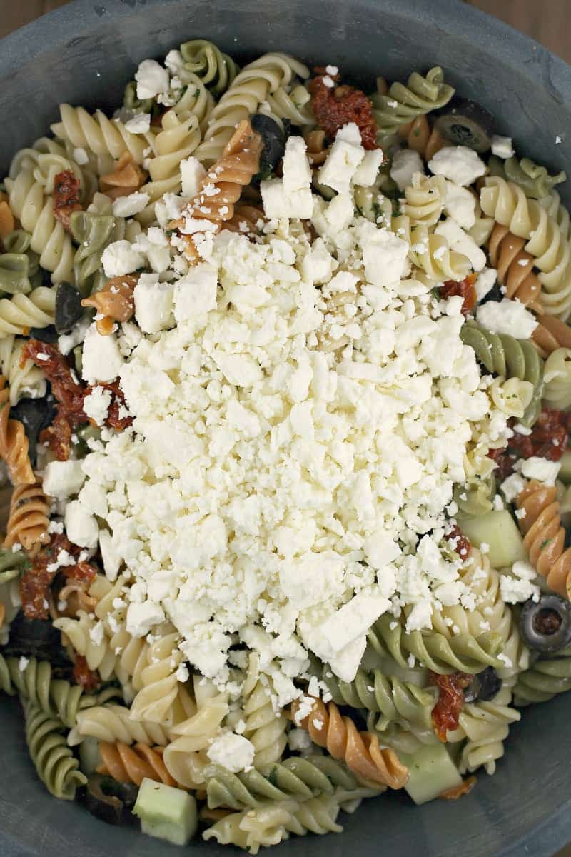 feta cheese on top of pasta salad in a bowl