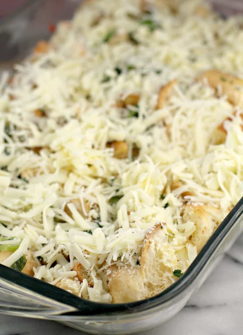 assembled casserole in clear glass bake dish topped with cheese prior to refrigeration and baking