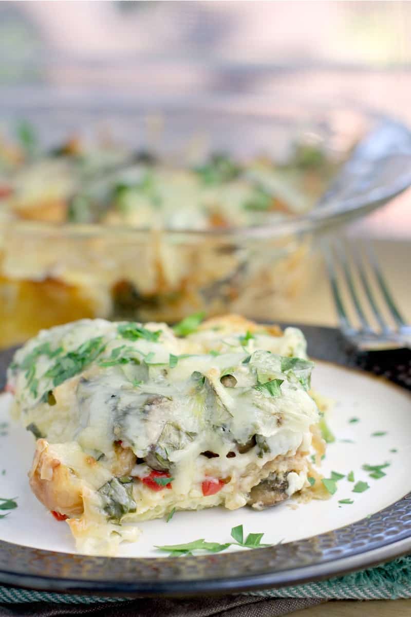 plated croissant breakfast casserole on a plate with fork; bake dish in the background