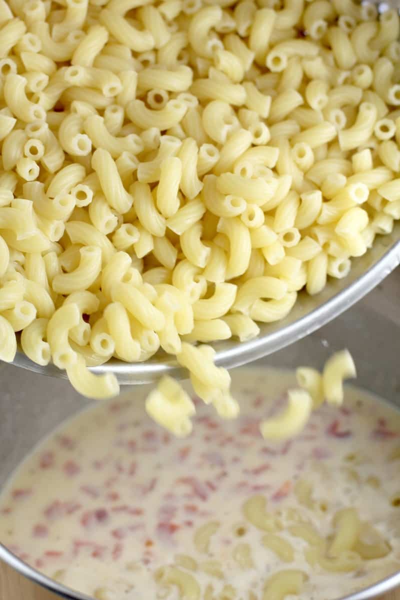cooked macaroni pouring into bechamel sauce