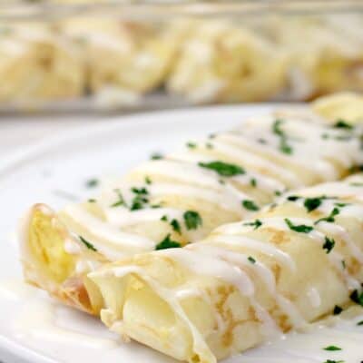 two plated crepes on white dish; casserole dish in background