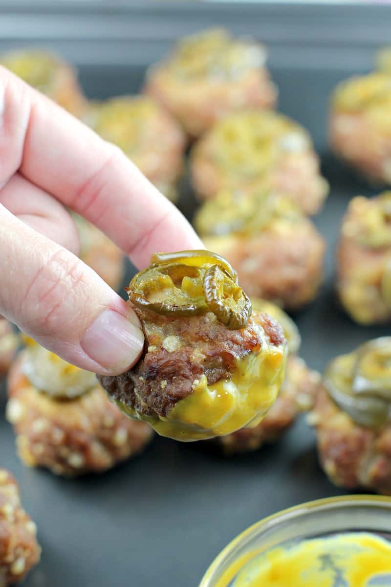 hand holding a smoked sausage ball dipped in honey mustard