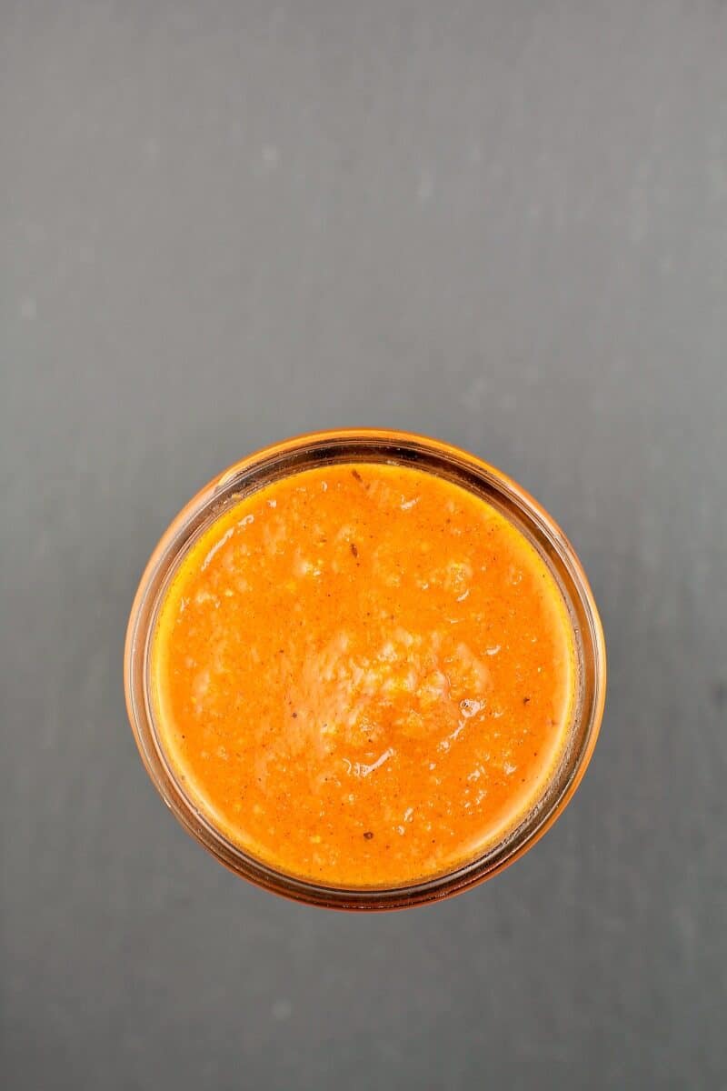 small mason jar filled with huevos ranchero sauce on slate background