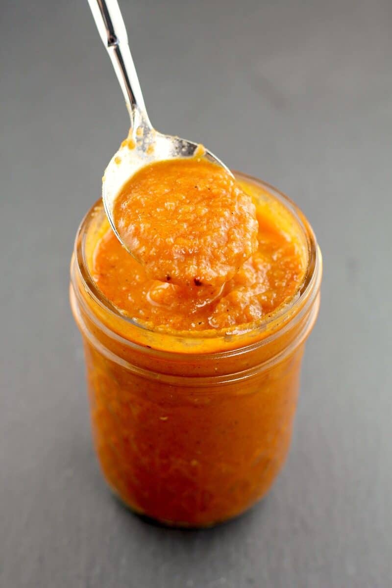 mason jar filled with huevos ranchero sauce with spoon lifting some up