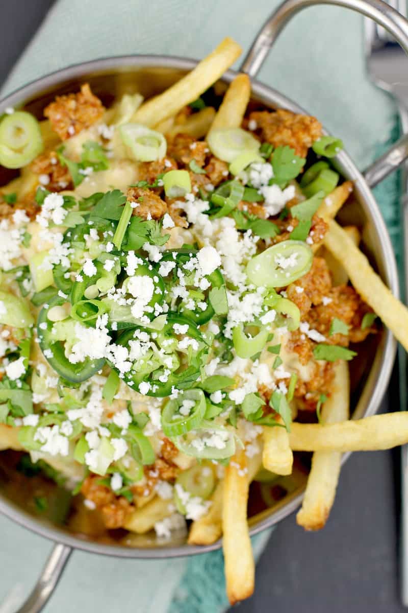 top down view of Mexican poutine in a metal dish on a blue napkin