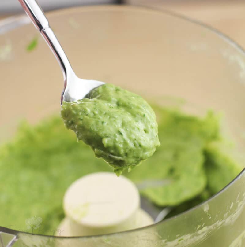 spoon scooping avocado sauce from a food processor