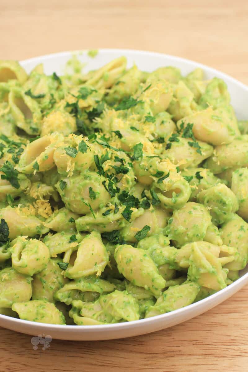 green pasta in white bowl on wood surface