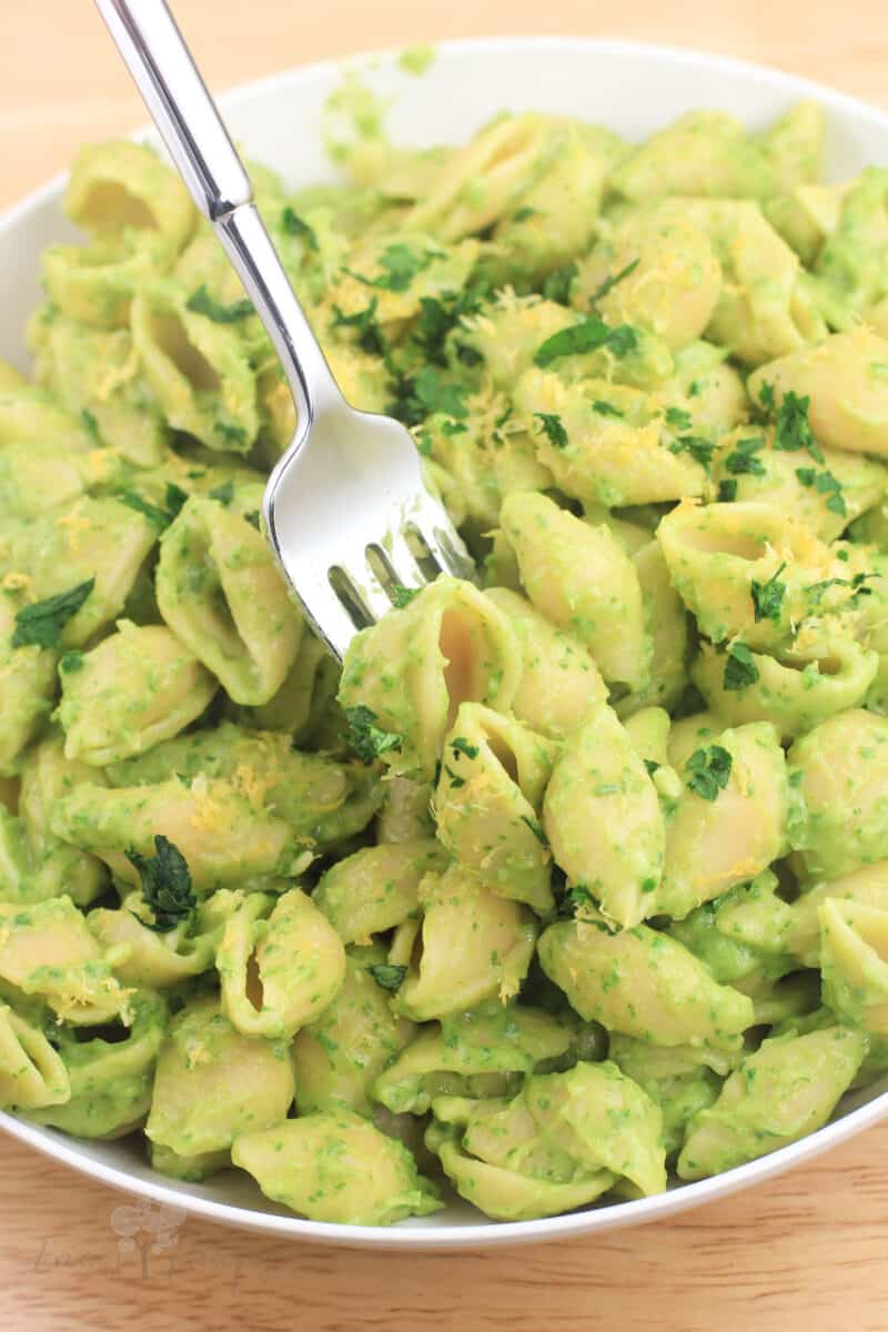 avocado spinach pasta in a white bowl with a fork
